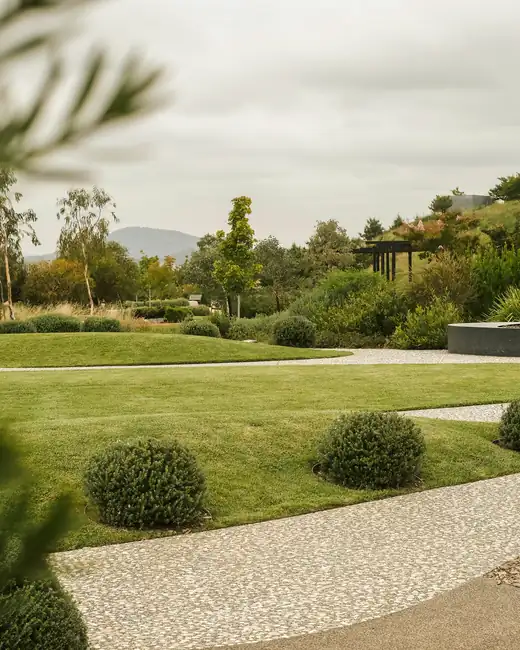 A broad mown lawn with clipped shrubs and a gravel path on an overcast day